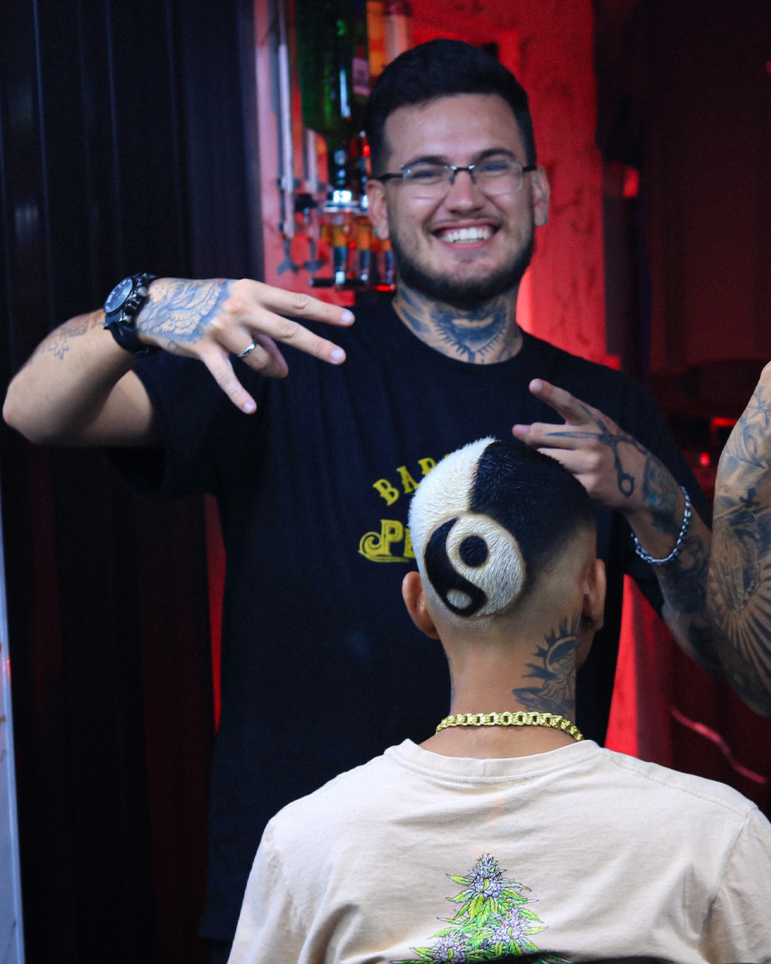 Daniel Pedrazzani posando em uma foto com um cliente de costas com um corte estilizado metade branco e metade preto juntando a um ying yang